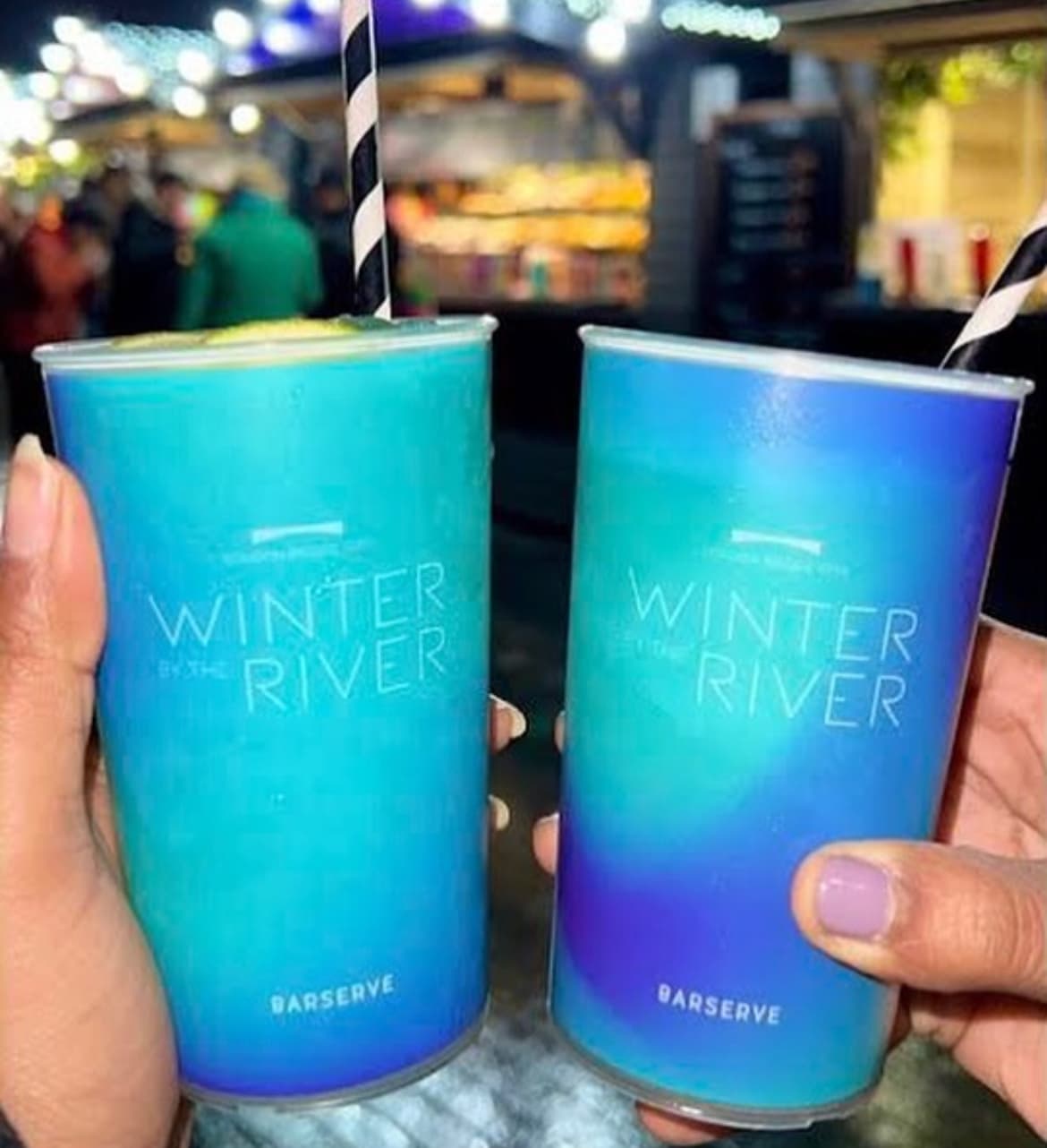 A variety of branded reusable festival cups stacked at a modern venue bar