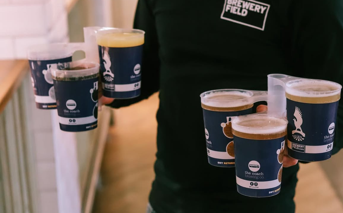 Multiple branded reusable cups carried at a venue, illustrating bulk supply